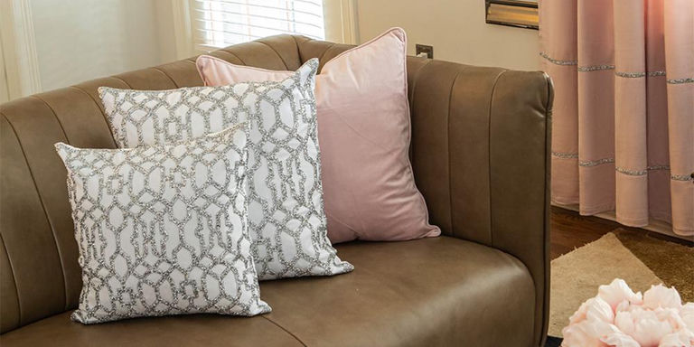 Silver patterned and blush pillows on a brown leather chair