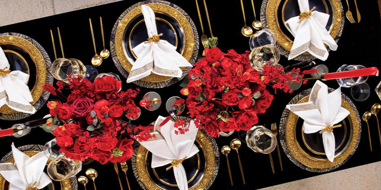 Overhead view of a black, gold, and red tablescape with floral centerpieces