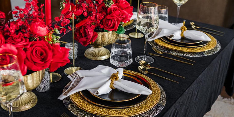 Black and gold tablescape with red floral centerpieces and white napkins