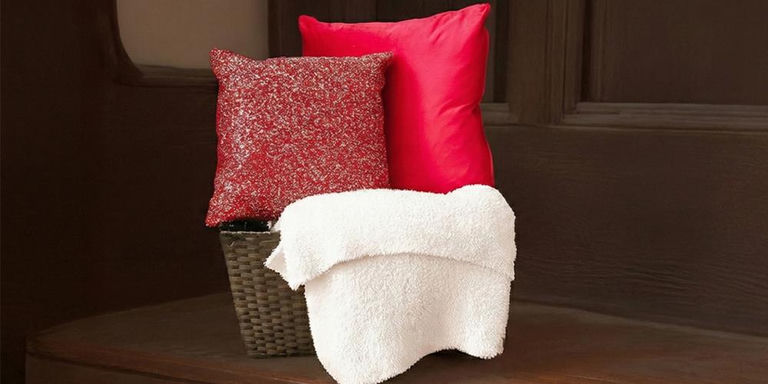 Sequin accent pillow, pink pillow, and white throw styled in a woven basket