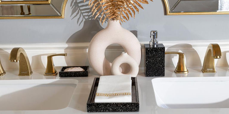 Double vanity styled with black bath accessories, sculptural vases, and gold fixtures