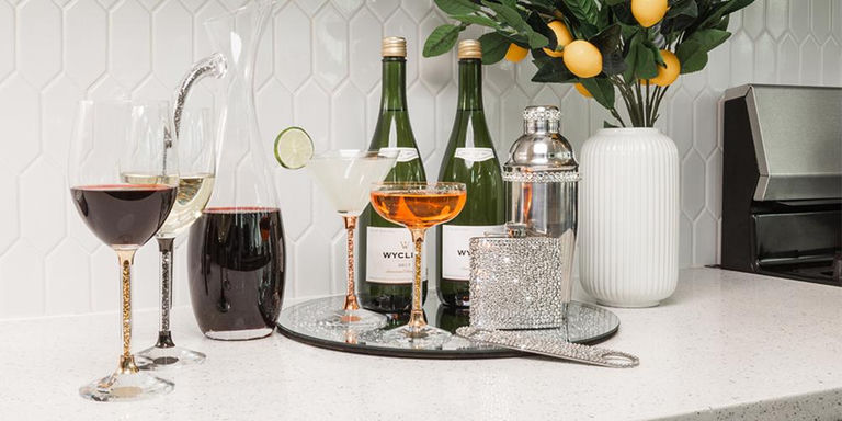 Luxury glassware and bar accessories on a mirrored home bar tray