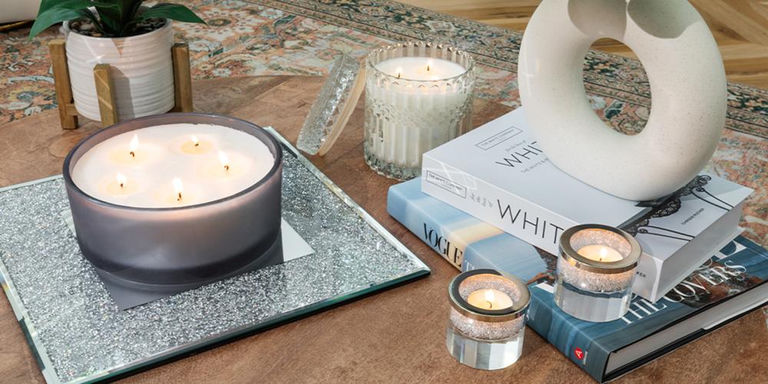 Styled coffee table with candles, mirrored tray, books, and a sculptural accent