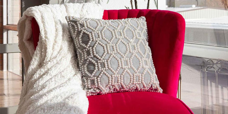 Silver lattice accent pillow on a pink velvet chair with a white throw