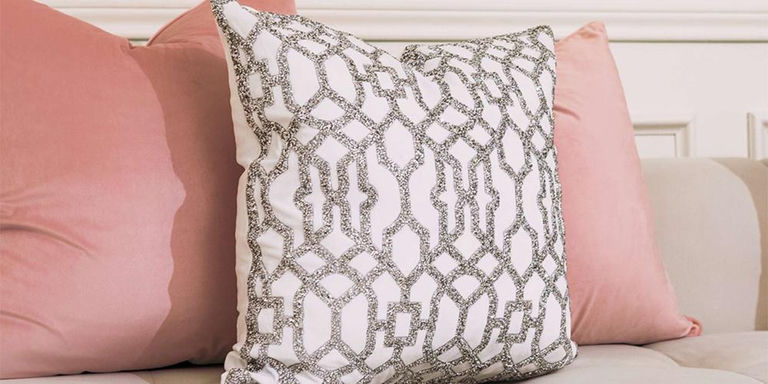 White lattice accent pillow styled between soft pink cushions