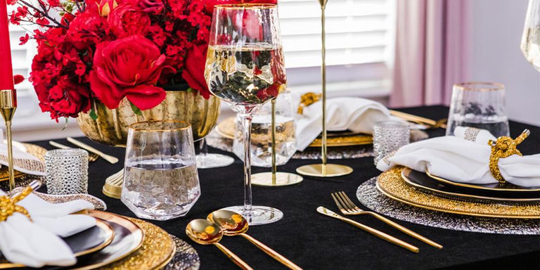 Close-up of a black and gold table setting with wine glasses and rhinestone accents