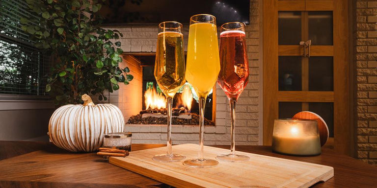 Apple cider mimosa in gold-rimmed toasting flute with cinnamon stick garnish on autumn table