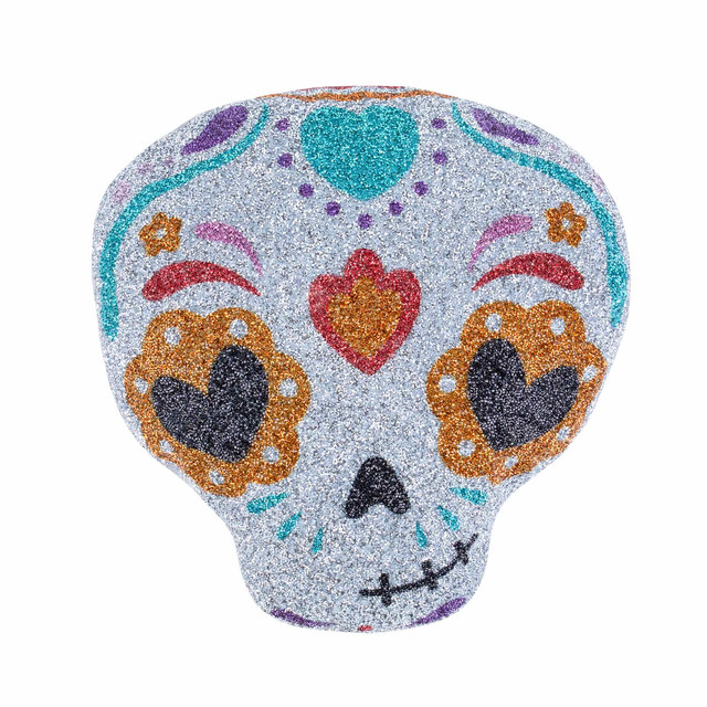 A glittery silver skull-shaped pillow with colorful floral and heart designs in orange black turquoise and purple accents.
