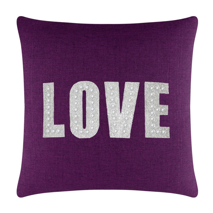 Purple square pillow featuring the word "LOVE" in rhinestones and faux pearls on a textured fabric surface.