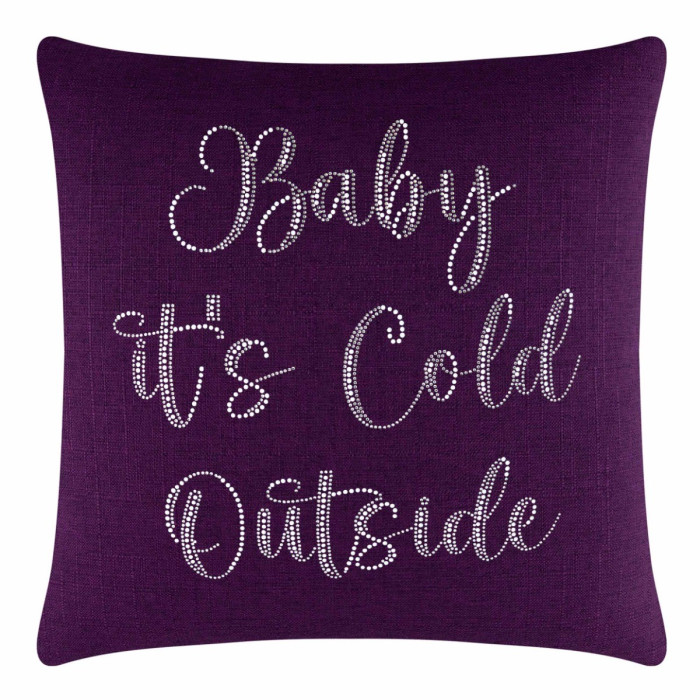 Purple square pillow with glass rhinestones spelling "Baby it's Cold Outside" in a cursive font on a textured fabric surface.