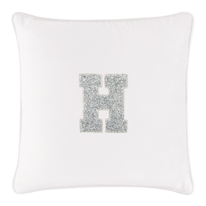 White velvet pillow featuring a silver rhinestone monogram "H" in the center with a piped edge.