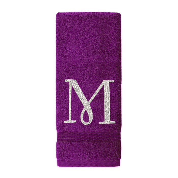 Purple cotton terry hand towel with a silver rhinestone monogram "M" and a textured border at the bottom.