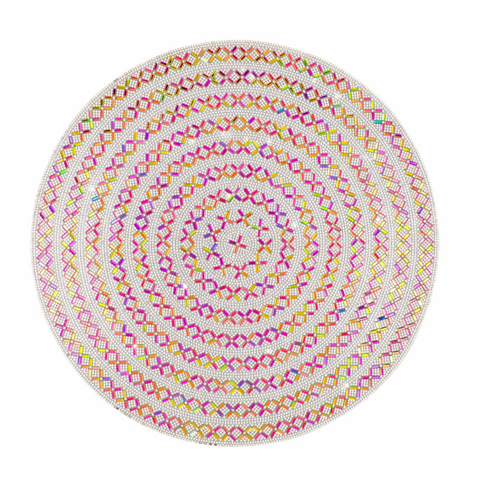 Round placemat featuring a silver background with concentric patterns of pink yellow and green rhinestones in diamond shapes.