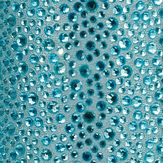 A tube of clear adhesive beside a clear pouch filled with silver and iridescent rhinestones of various sizes and shapes.