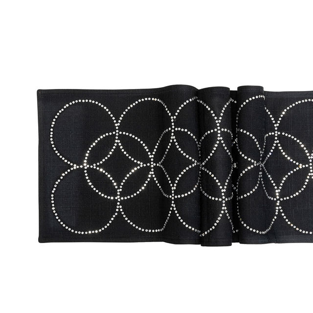 Black table runner with overlapping circles made of glass rhinestones on a textured fabric surface.
