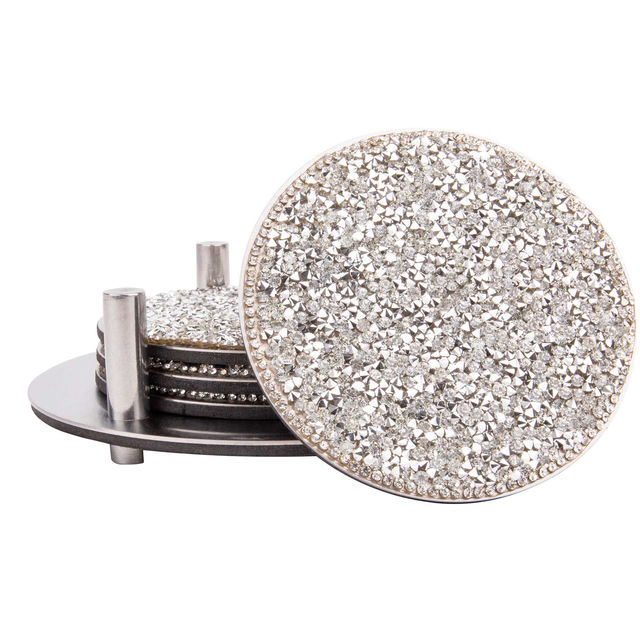 Set of four round stainless steel coasters with a rhinestone-studded surface and a foam backing displayed in a metal holder.