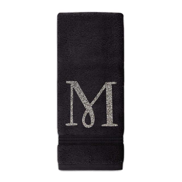 White plush cotton terry hand towel with a sparkling gold rhinestone monogram "M" and decorative horizontal stripes at the bottom. White plush cotton terry hand towel with a sparkling gold rhinestone monogram "M" and decorative horizontal stripes at the bottom.