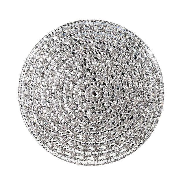 Round silver pillow with a plush velvet texture featuring a spiral design of rhinestones and mirrored embellishments.