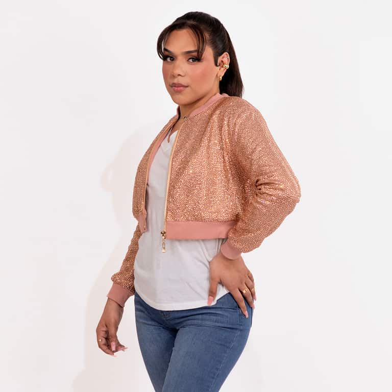 Woman wearing a pink rhinestone cropped bomber jacket over a white top and jeans