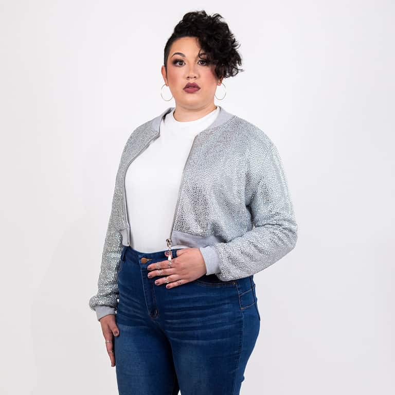 Silver rhinestone cropped bomber jacket worn open over a white top with jeans