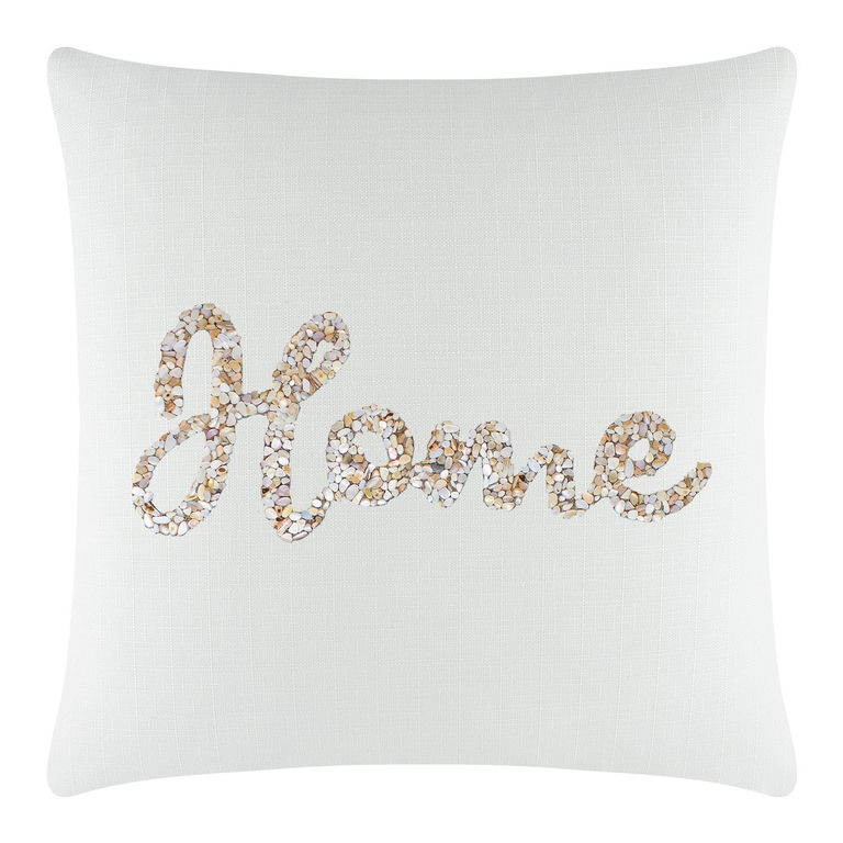 White square pillow with textured fabric featuring "Home" in seashell design with beige and cream tones.