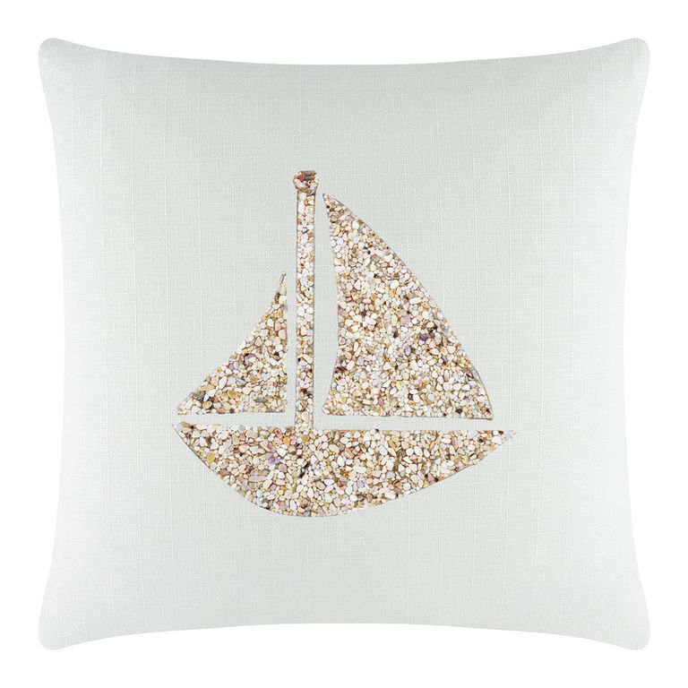 White textured pillow featuring a seashell sailboat design in beige and gold embellishments.