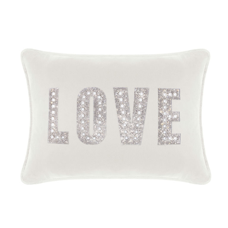 White velvet pillow featuring the word "LOVE" in rhinestones and faux pearls with a plush rectangular shape and piped edges.