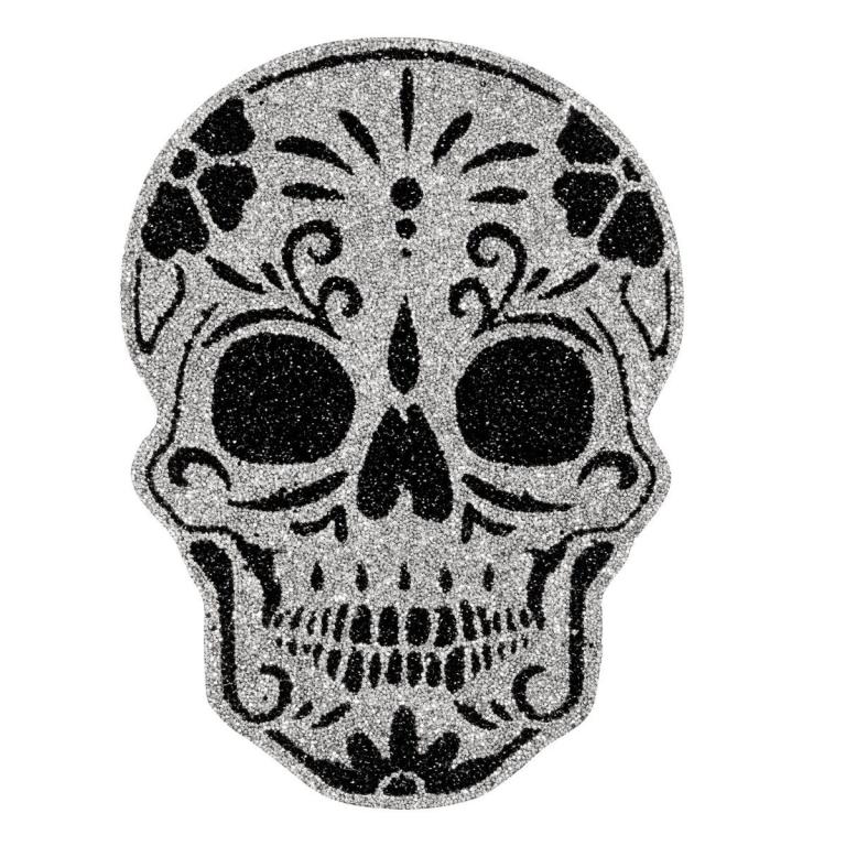 A silver glitter skull placemat with black floral designs and large eye sockets featuring intricate detailing and a smooth texture.