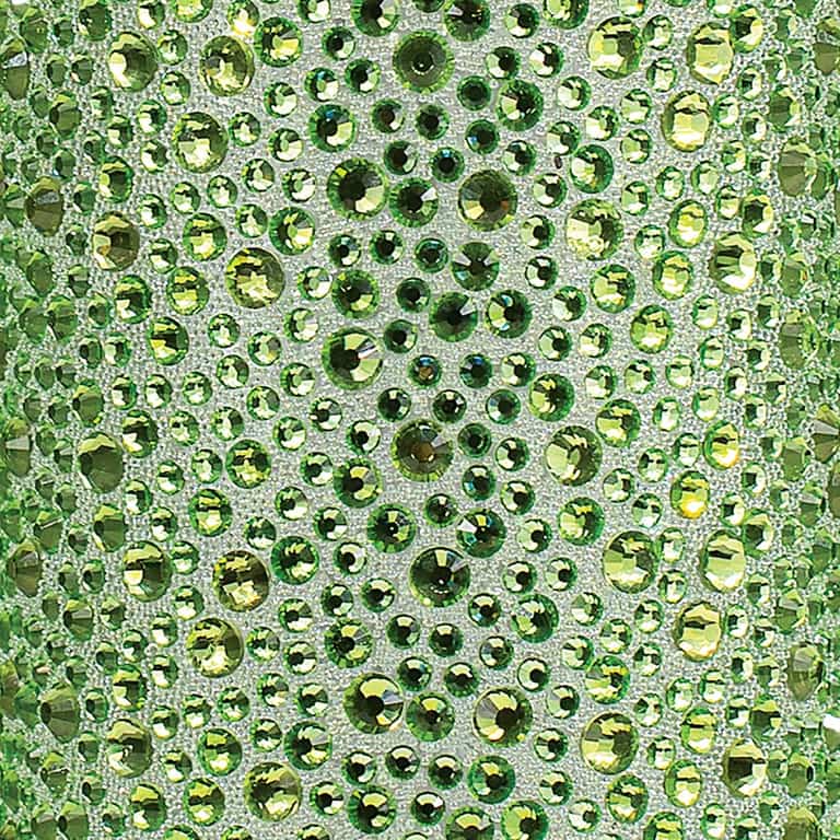 Lime green rhinestones in various sizes arranged on a textured silver background with intricate detailing.
