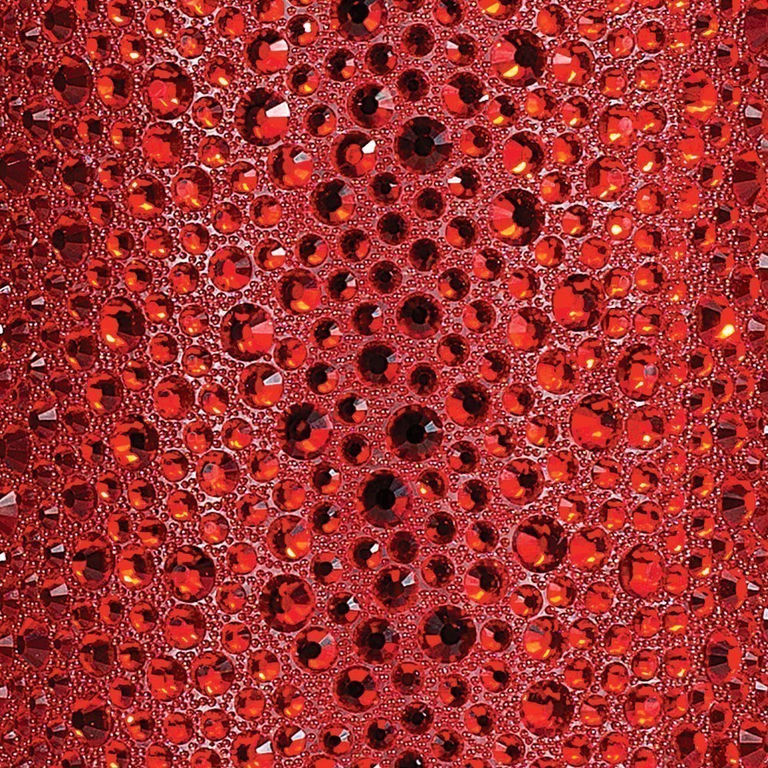 Red fabric adorned with various sizes of red rhinestones featuring a shiny faceted surface and a textured background.