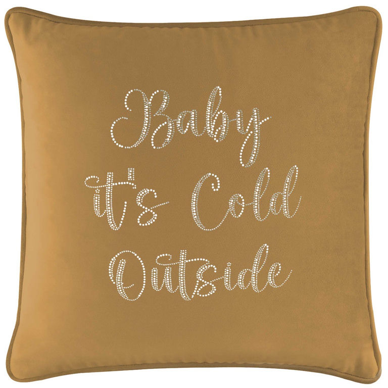 Gold velvet pillow with glass rhinestones spelling "Baby it's Cold Outside" in a cursive font on a smooth surface.