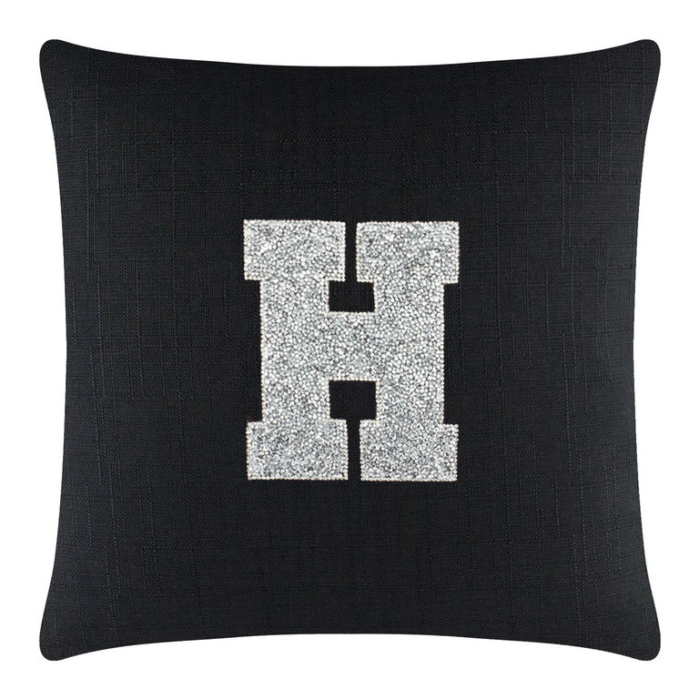 Black textured pillow featuring a large rhinestone-embellished silver letter "H" in the center.