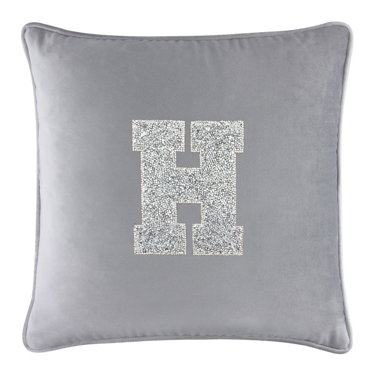 Silver velvet pillow with a rhinestone-embellished letter "H" in the center and a piped edge.