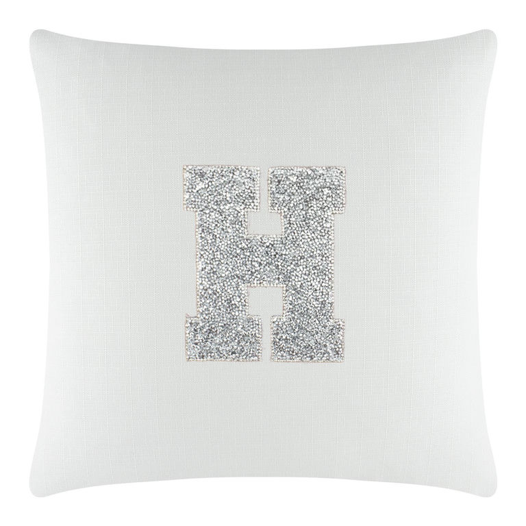 White textured pillow featuring a large rhinestone-embellished letter "H" in silver.