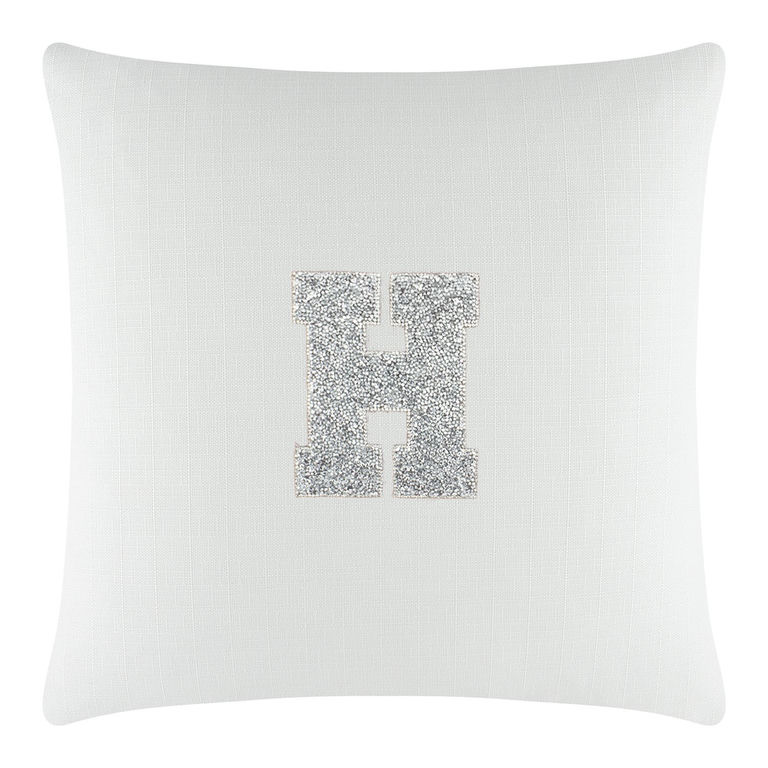 White square pillow with a textured surface featuring a rhinestone-embellished letter "H" in silver.