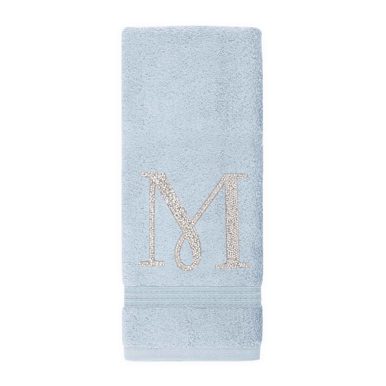 Aqua cotton terry hand towel with a rhinestone monogram "M" and a textured striped border at the bottom.