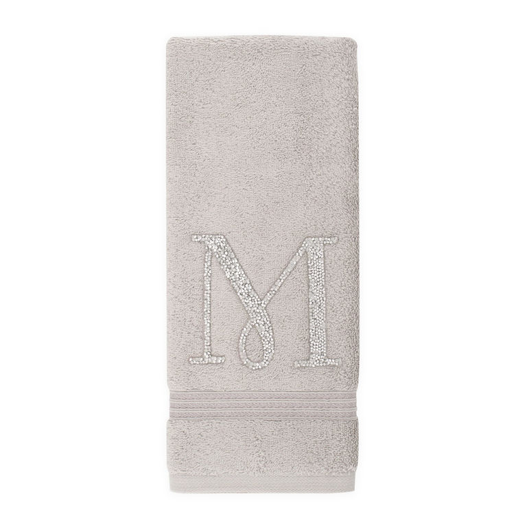 Gray plush cotton terry hand towel with a rhinestone monogram "M" and a silver embroidered trim at the bottom.