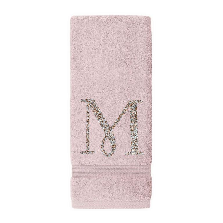 Plush pink cotton terry hand towel with a sparkling rhinestone monogram "M" and decorative stripes at the bottom.