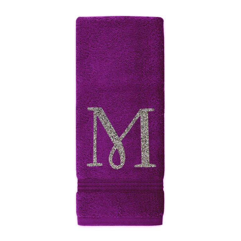 Plush purple cotton terry hand towel with a sparkling rhinestone monogram "M" and decorative trim at the bottom.