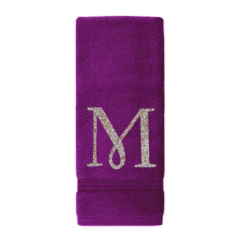 Plush purple cotton terry hand towel with a sparkling rhinestone monogram "M" and a textured border at the bottom.