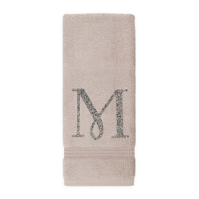 Taupe cotton terry hand towel with a sparkling rhinestone monogram "M" and a horizontal charcoal stripe at the bottom.