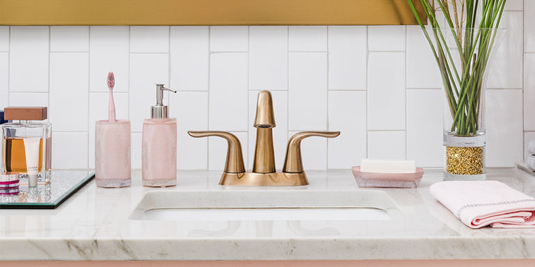 Bathroom&amp;&#x23;x20&#x3B;vanity&amp;&#x23;x20&#x3B;with&amp;&#x23;x20&#x3B;pink&amp;&#x23;x20&#x3B;bath&amp;&#x23;x20&#x3B;accessories,&amp;&#x23;x20&#x3B;gold&amp;&#x23;x20&#x3B;faucet,&amp;&#x23;x20&#x3B;and&amp;&#x23;x20&#x3B;white&amp;&#x23;x20&#x3B;subway&amp;&#x23;x20&#x3B;tile