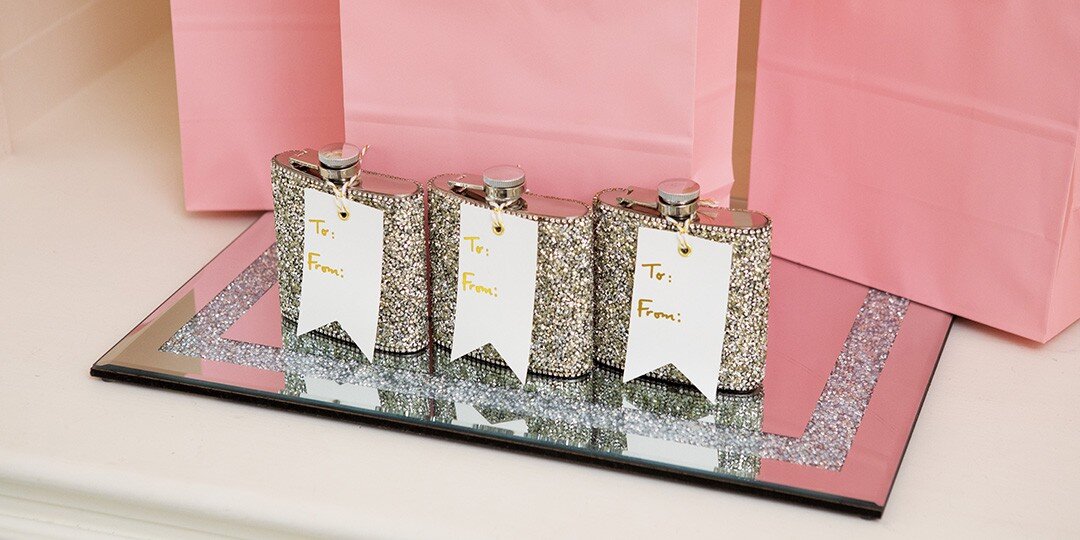 Three&amp;&#x23;x20&#x3B;sparkly&amp;&#x23;x20&#x3B;rhinestone-covered&amp;&#x23;x20&#x3B;hip&amp;&#x23;x20&#x3B;flasks&amp;&#x23;x20&#x3B;arranged&amp;&#x23;x20&#x3B;on&amp;&#x23;x20&#x3B;a&amp;&#x23;x20&#x3B;mirrored&amp;&#x23;x20&#x3B;tray,&amp;&#x23;x20&#x3B;each&amp;&#x23;x20&#x3B;adorned&amp;&#x23;x20&#x3B;with&amp;&#x23;x20&#x3B;white&amp;&#x23;x20&#x3B;gift&amp;&#x23;x20&#x3B;tags&amp;&#x23;x20&#x3B;featuring&amp;&#x23;x20&#x3B;gold&amp;&#x23;x20&#x3B;