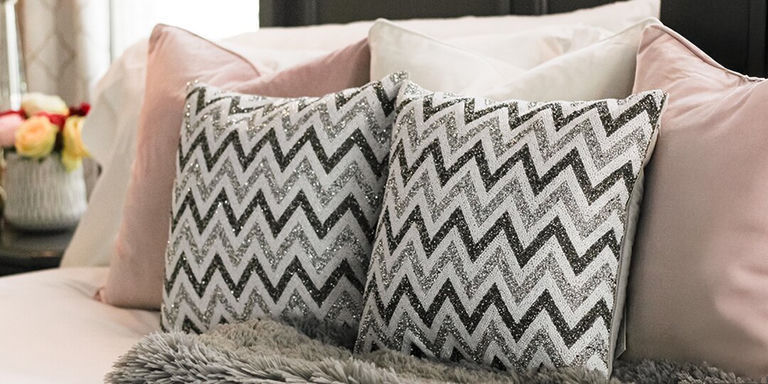 cojines de tiras de strass estilo chevron en una cama de terciopelo rosa y marfil