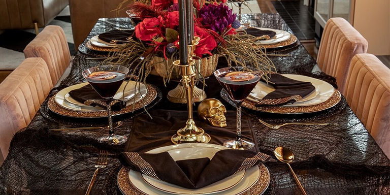 close-up of bat-folded napkin on black and gold place setting with skull decor
