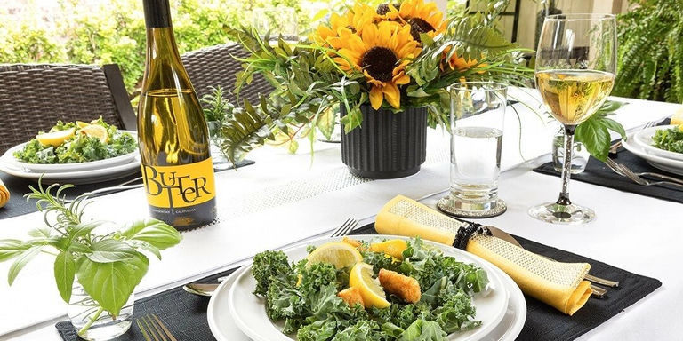 Spring table setting with sunflowers, greenery, and yellow accents on a white tablecloth