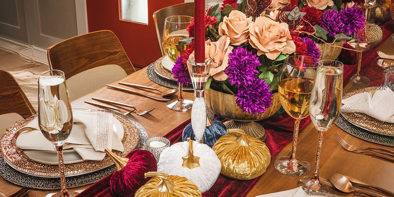 elegante mesa de otoño con platos de carga de pedrería, candelabros Vetrina, calabazas de terciopelo y centro de mesa floral