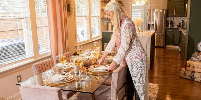host setting a glam fall tablescape with gold accents and velvet chairs