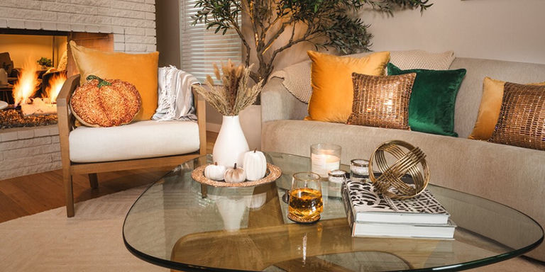 cozy glam living room setup with rhinestone pillows, pumpkin accents, and glass coffee table