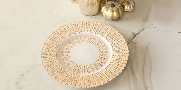gold studded charger plate styled with glam fall decor on marble countertop